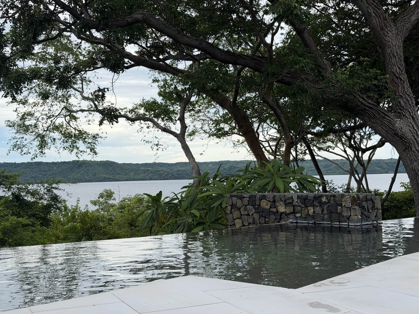 The adults-only infinity pool with its edge meeting the trees and Culebra Bay beyond, under a soft grey sky
