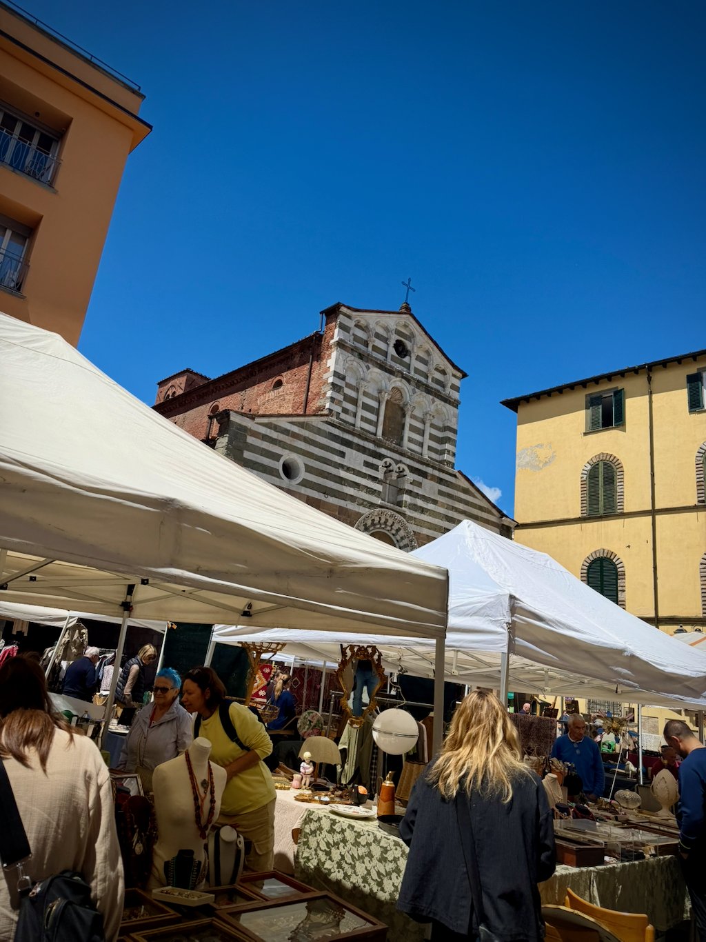 Market stalls filling the square in front of a striped church facade in Lucca
